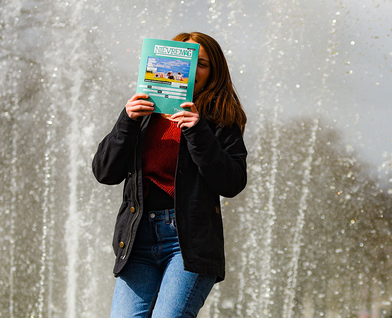 Femme tenant Nièvre Mag devant une fontaine